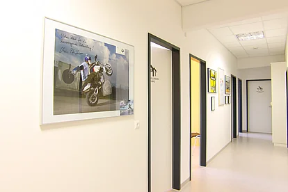 Heller Praxisflur mit gerahmten Sportbildern an der Wand